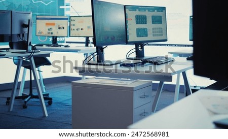 Empty telecommunications control room with workstations, coworking space equipped with a big screen and modern devices used in organizational daily tasks and projects. Camera B.