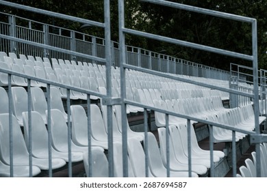 Empty temporary stadium bleachers, gray metal seats, neutral background, no spectators, industrial and minimalistic sports architecture.