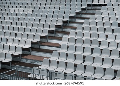 Empty temporary stadium bleachers, gray metal seats, neutral background, no spectators, industrial and minimalistic sports architecture.