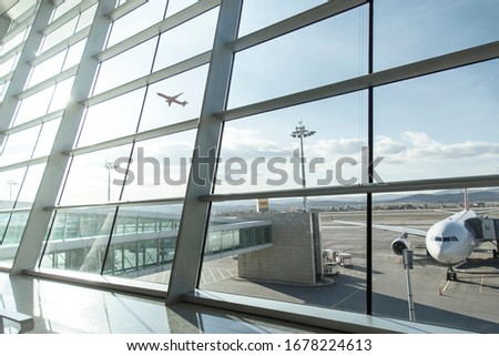 An empty terminal, aircrafts are waiting and preparing for their next flight and one of them taken off