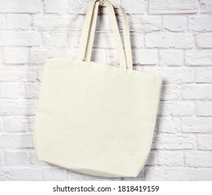 empty textile eco bag hanging against a white brick wall background, no plastic, zero waste  - Shutterstock ID 1818419159