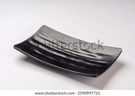 An empty, textured, rectangular black melamine plate with a striped pattern, suitable for serving sushi, appetizers, or desserts isolated on plain White background 