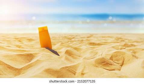 Empty Textured Sand Beach In Front Of Summer Sea With Suncream Bottles.