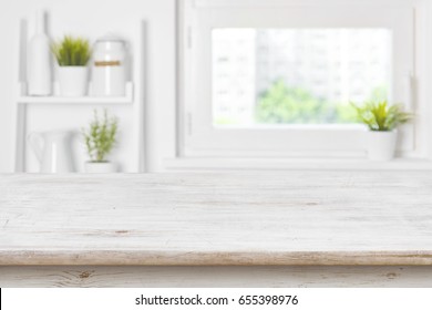 Empty textured wooden table and kitchen window shelves blurred background