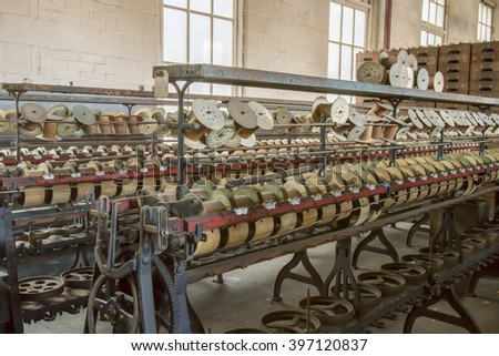 Empty thread spools on antique machinery in turn of the century silk throwing factory.