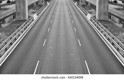 An empty three lane carriageway, processed in monochrome.
