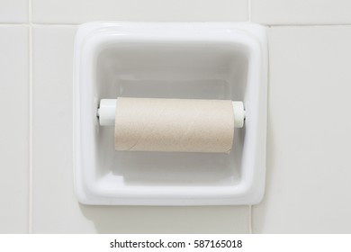 Empty Toilet Paper Roll Mounted On A Tiled Wall