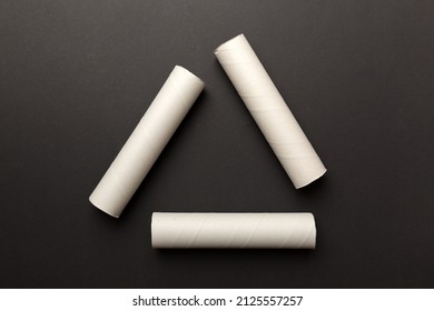Empty toilet paper roll on colored background. Recyclable paper tube with metal plug end made of kraft paper or cardboard in the form of a recycling sign.