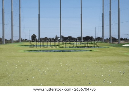 Empty Topgolf driving range with artificial turf and target circles under a clear blue sky, May 30, 2021