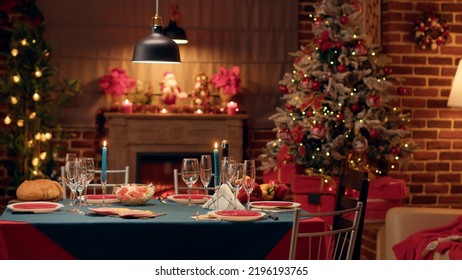 Empty traditional Christmas dinner table inside decorated living room with holiday garlands and dinnerware. Interior of traditional and authentic season cozy setting celebrating religious event. - Powered by Shutterstock