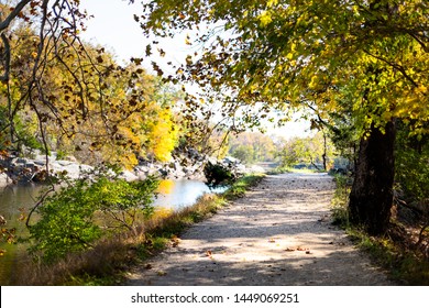 Empty Trail Path During Autumn Potomac River In Great Falls, Maryland With Colorful Foliage And Fallen Leaves On Road By Canal