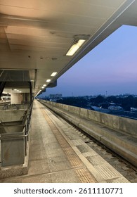 Empty train platform at dusk. Modern architecture, leading lines, urban transport. Evening sky, cityscape view. Travel and infrastructure concept.