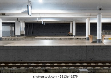 Empty train station platform under bright lighting.