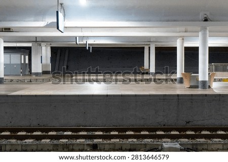 Empty train station platform under bright lighting.