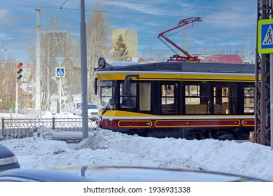 An empty tram rides through the intersection on a cold winter day