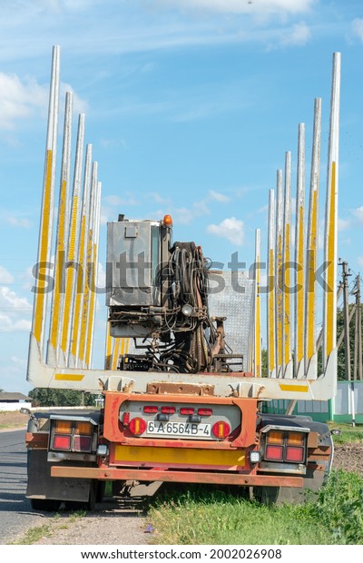 An empty truck is standing on the side of the\
road waiting for the cargo to be loaded. On the road, an empty\
logging truck with a manipulator on a sunny summer day. logging\
truck close-up.