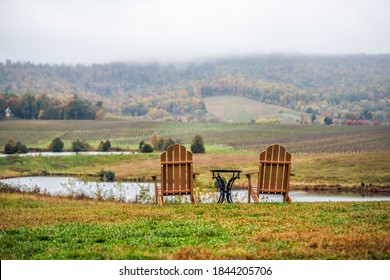 Empty two romantic wooden chairs in autumn fall foliage season countryside at Charlottesville winery vineyard in blue ridge mountains of Virginia with cloudy sky day