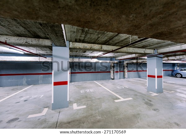 Empty underground car park with a solitaire car in\
the right corner