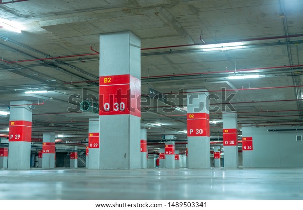 Empty underground car parking lot. Underground car\
parking garage at shopping mall or international airport. Indoor\
parking area. Concrete basement floor parking garage. Interior\
building in the city.