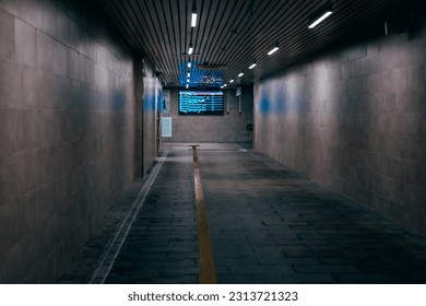Empty underground passage under the highway. Gray illuminated underground passage without people. Underground tunnel lit by lamps.