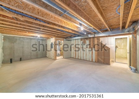 Empty unfinished large basement with concrete flooring and wooden frames