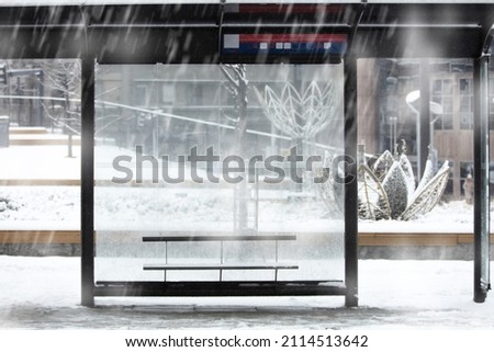 Empty urban bus stop during heavy witner snowfall.