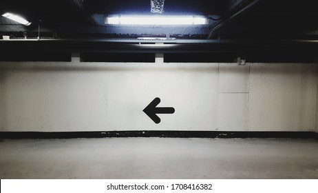 Empty Vacant Indoor Illuminated Underground Parking Lot Carpark Concrete Wall With Arrow