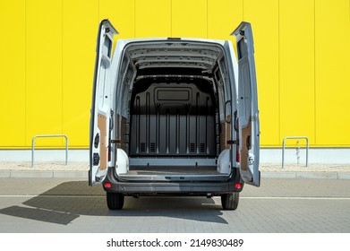 Empty van with open doors in front of a yellow wall