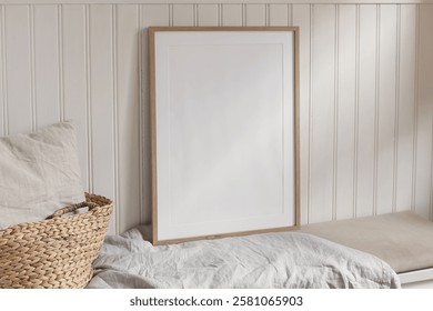 Empty vertical portrait A2 thin wooden frame mockups with linen cloth on bench. White beadboard wainscot wall paneling background. Straw French basket, linen pillow cushion. Scandinavian interior home