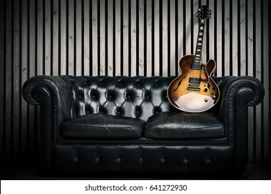 Empty Vintage Sofa And Electric Guitar With Modern Wood Wall Recording Studio Background. Music Concept With Nobody 