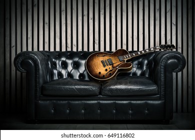 Empty Vintage Sofa And Electric Guitar With Modern Wood Wall Recording Studio Background. Music Concept With Nobody 