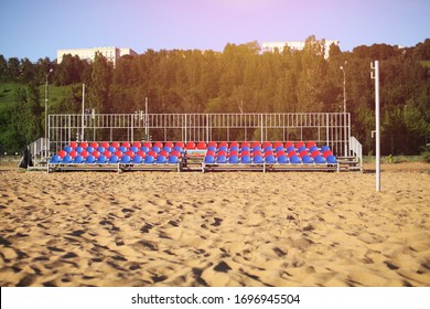 Empty Volleyball court at the city beach. Nobody is on the summer beach due to quarantine infection. Outdoor sports competition. Close up view of plastic chairs on the stadium bench.