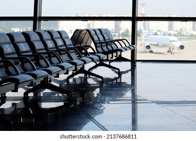 Empty waiting chairs in the airport building against the plane on runway. Ban on flights over Europe from Russia, travel during quarantine at coronavirus pandemic