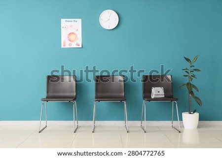 Empty waiting room with chairs and clock on blue wall