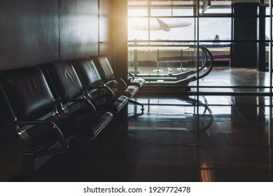 An Empty Waiting Room Of A Modern Airport Terminal Departure Or Arrival Area With A Row Of Leather Metal Armchairs And A Travelator In The Distance; An Airplane Taking Off Outside The Window