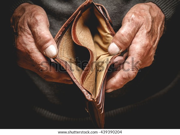 Empty wallet in the hands of an elderly man.\
Poverty in retirement\
concept