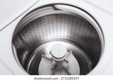 Empty washing machine drum interior. Stainless steel washer inside view. Clean laundry appliance. Modern household equipment. Minimal white design. Top view perspective. Domestic washing technology.