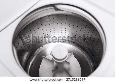 Empty washing machine drum interior. Stainless steel washer inside view. Clean laundry appliance. Modern household equipment. Minimal white design. Top view perspective. Domestic washing technology.