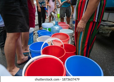 Empty water buckets waiting for fresh water from emergency mobile tank truck - Shutterstock ID 1873637479