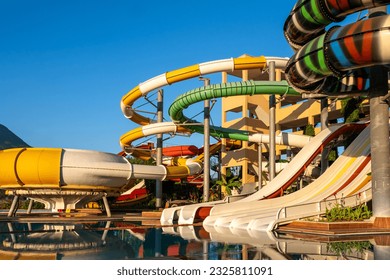 Empty Water park for kids in a luxury hotel near the sea. Water park, bright multi-colored slides with a pool. A water park without people on a summer day with a beautiful, cloudy blue sky. Aquapark 