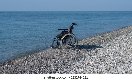 An empty wheelchair on a rocky seashore. - Powered by Shutterstock