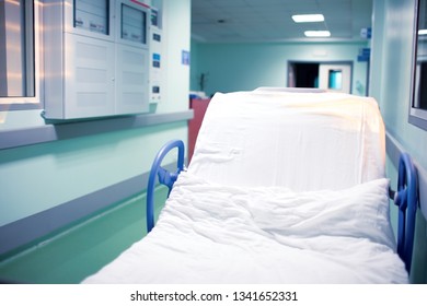 Empty Wheeled Bed In The Hospital Hall Near The Reception Desk.