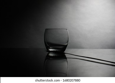 Empty whiskey glass on a glass table , black background , dark background