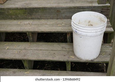 Empty White 5 Gallon Bucket Sitting On Wood Porch Steps