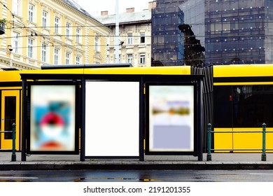 Empty White Ad Panel And Light Box At A Tram Stop With Urban Background. Billboard For Mockup And Place Holder Sample Image. Advertising Background. Glass And Aluminum Structure. Urban Scene.