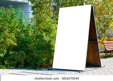 Empty white advertising layout on a city street in summer.Advertising wooden Billboard with a copy of the space.mock up, illuminated by the sun.