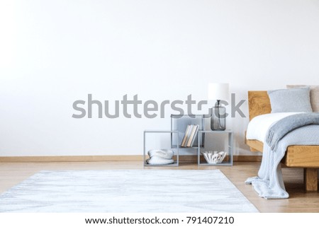 Empty white bedroom interior with bed with woolen blanket, shelves and snowy white carpet