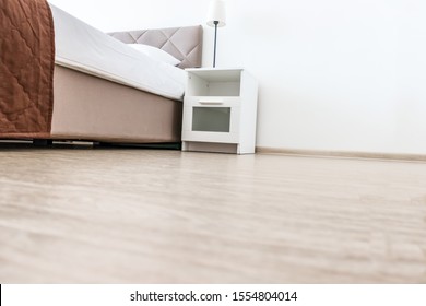 Empty White Bedroom Interior With Copy Space On The Floor, Low Angle Shot Of A Bed And A Nightstand.