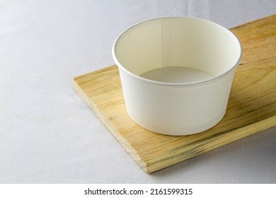 Empty, White And Blank Cardboard Or Cardboard Ice Cream Cup Mockup Or Mock Up Template On Wooden Cutting Board On Clean Background