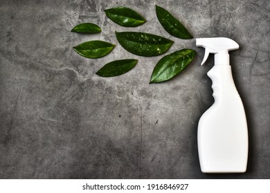 Empty White Bottle Mockup For Cleaning. Eco Spray Bottle For Safe Cleaning With Green Leaves On Concrete Background. Copy Space, Flat Lay. Creative Composition.